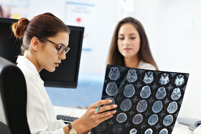 Doctora evaluando una tomografía computarizada junto al paciente