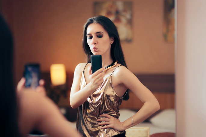 woman in a metallic dress taking selfie in the mirror