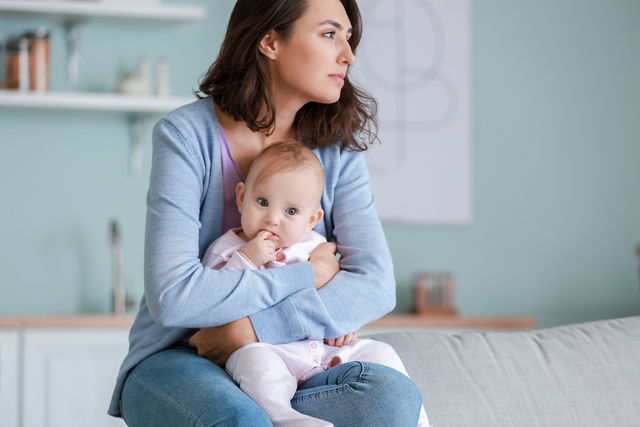 Mãe com bebê no colo olhando ao longe