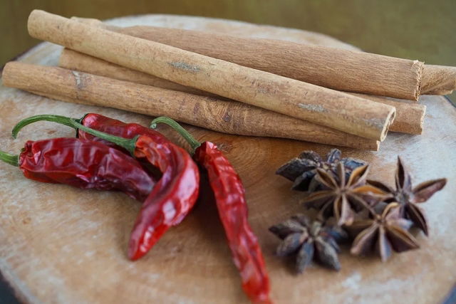 Canela em pau, pimenta vermelha e anis estrelado sobre uma tábua de madeira