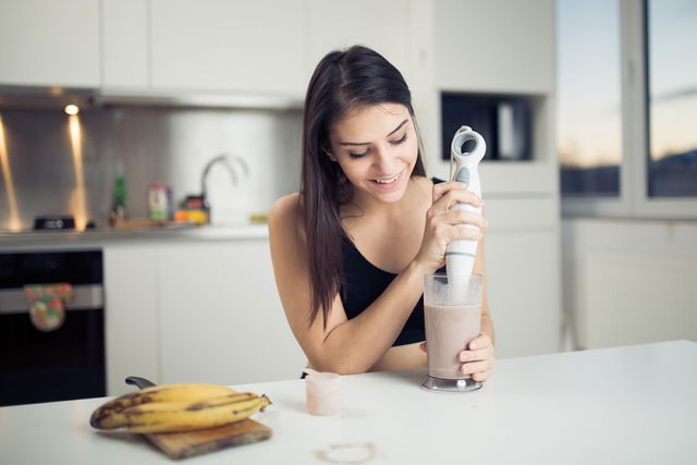 Mujer preparando un batido de plátano para evitar el SPM