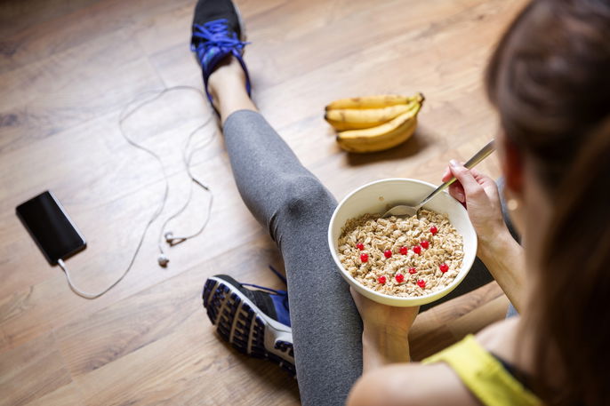 Woman in workout clothes eating a meal.
