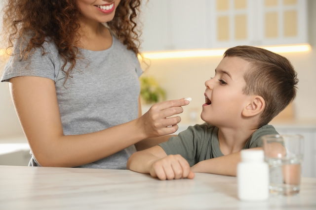 Mãe dando comprimido para criança