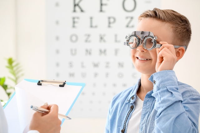 Criança fazendo o teste de acuidade visual com óculos graduado lendo o letreiro