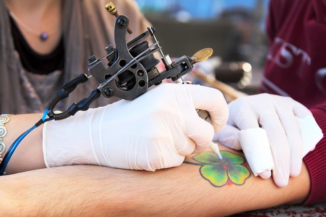 Tatuadora fazendo tatuagem no braço de uma pessoa