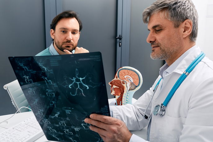 Médico explicando o resultado de um exame de imagem dos vasos sanguíneos intracranianos para o pacie