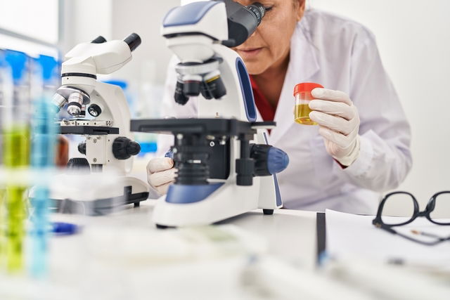 Técnico de laboratorio observando una muestra de orina bajo un microscopio