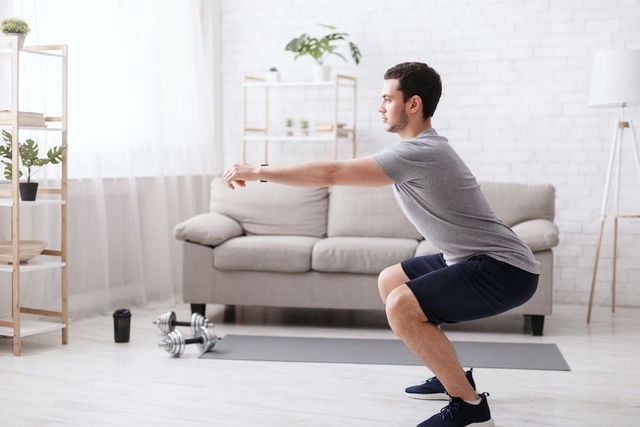 Homem realizando agachamento livre em casa