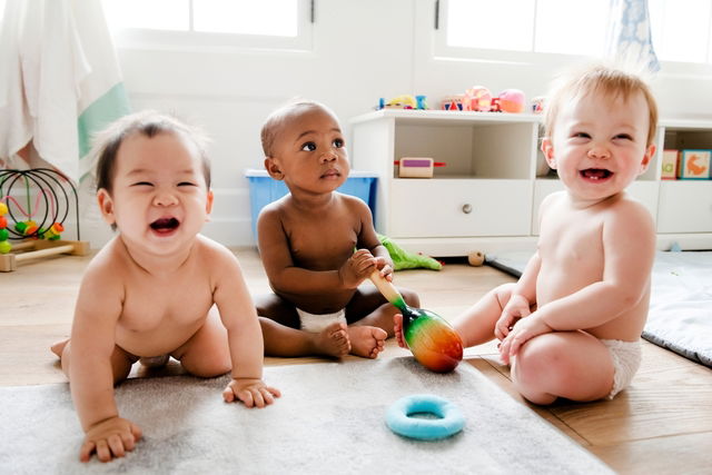 Três bebês sentados no chão brincando