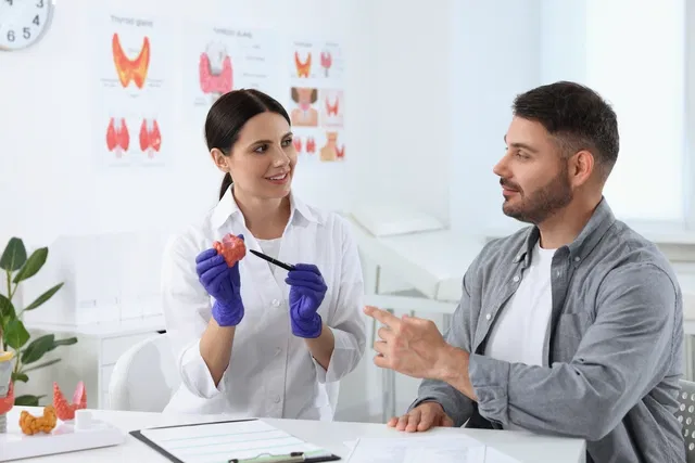 Endocrinólogo explicando la tiroides a un paciente en el consultorio