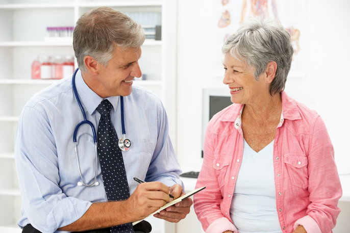 middle-aged male doctor smiling with older female patient