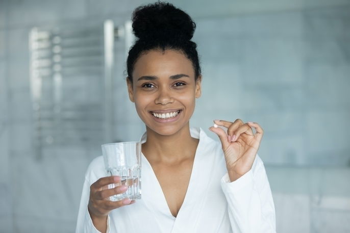 woman smiling and holding up a pill