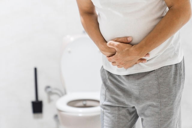 Persona en el baño con las manos en el abdomen