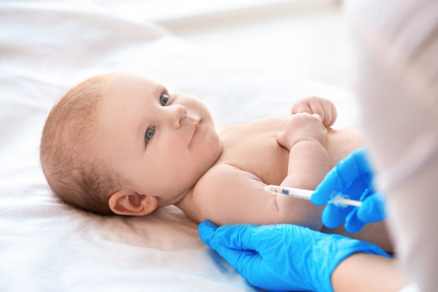 Medico aplicando vacina no braço direito do bebê