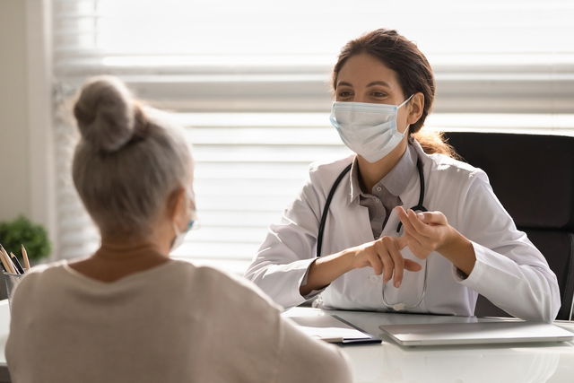 Médica explicando medidas de prevenção para uma paciente no consultório durante a pandemia