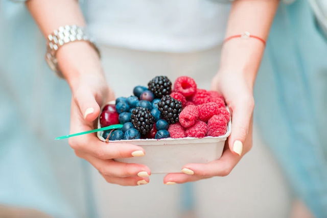 Mulher segura um bowl com fruts vermelhas