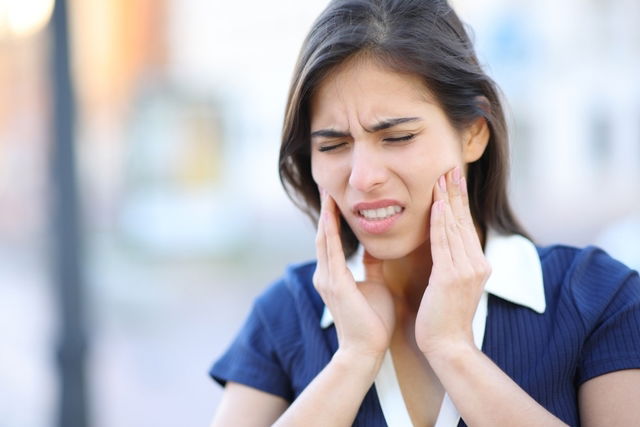 Woman holding jaw in pain