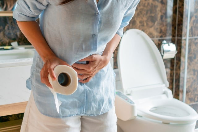 Person gripping abdomen while in bathroom