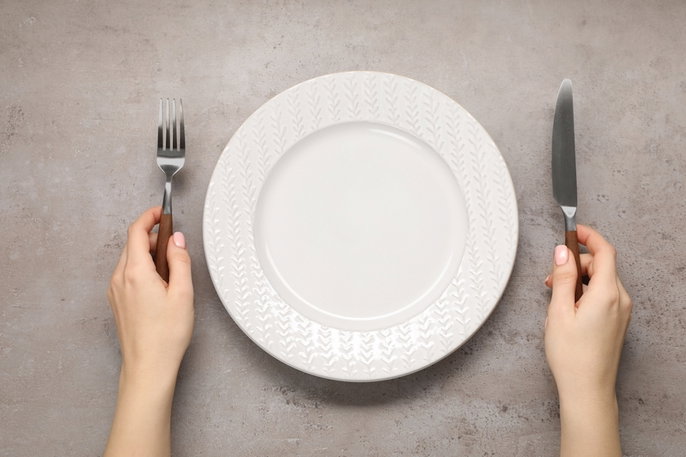 empty plate with hands holding knife and fork
