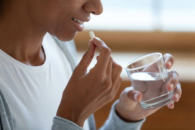 Mujer tomando un comprimido de Terramicina con un vaso de agua