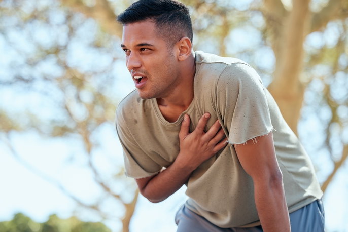 Man hunched over with hand on his chest