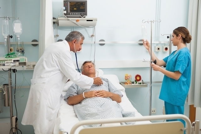 man in a hospital bed with male doctor and female nurse