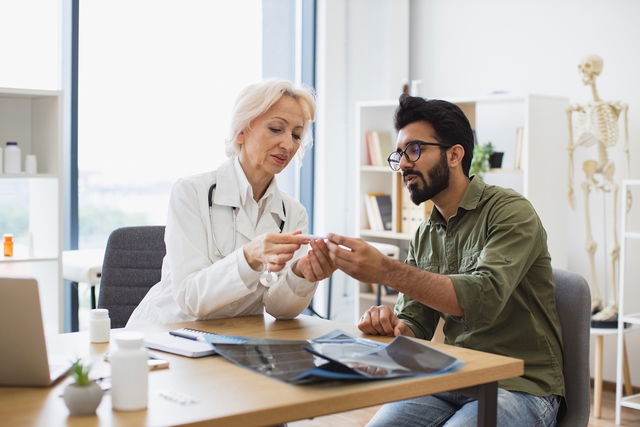 Médica monstrando a medida da temperatura obtida para o paciente no termômetro 