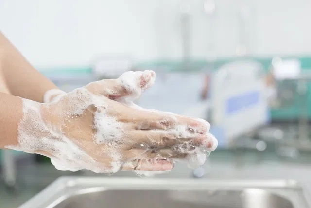 Persona lavando la herida de mordedura de rata con agua corriente y jabón en las manos