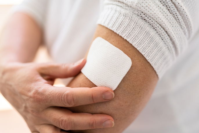 Patient applying patch to arm