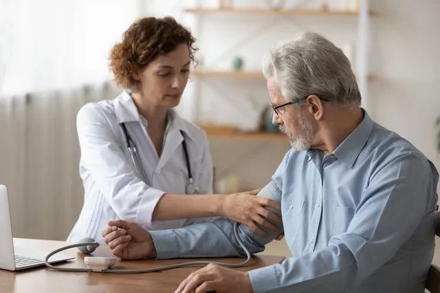 Doctora midiendo la presión a un adulto mayor