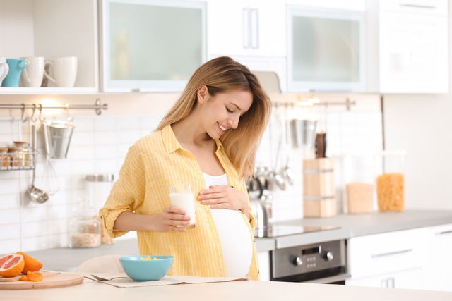 Grávida sorrindo passando a mão na barriga