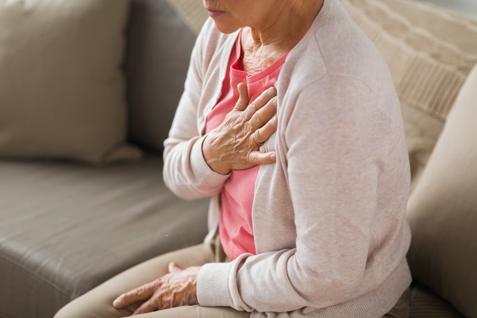woman sitting on couch clutching her chest