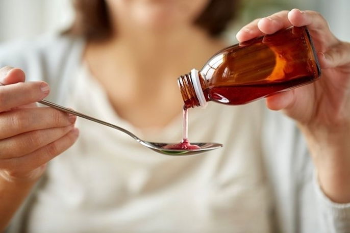 Woman pouring cough syrup onto spoon