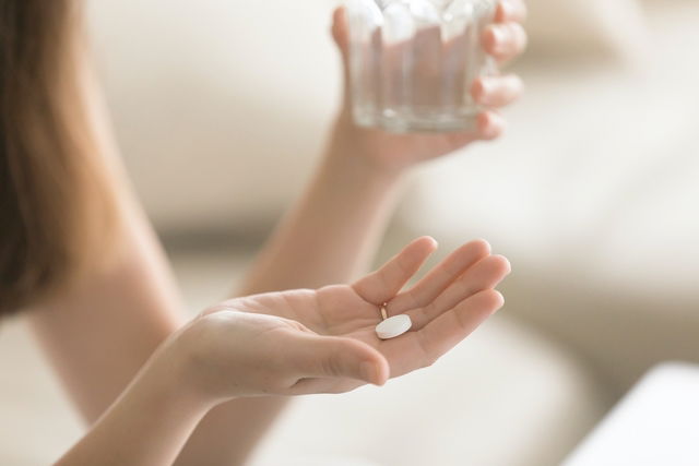 Woman holding pill in hand