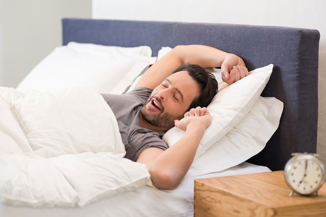 homme en train de se réveiller dans le lit