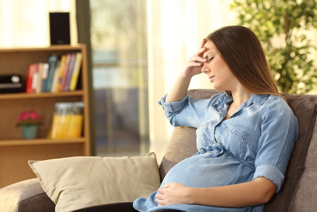 Pregnant woman sitting and holding head