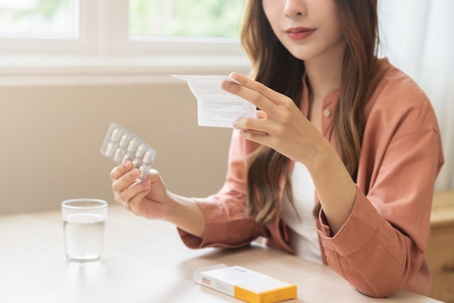 Mujer con un blíster de levetiracetam en la mano, leyendo la receta médica con un vaso de agua